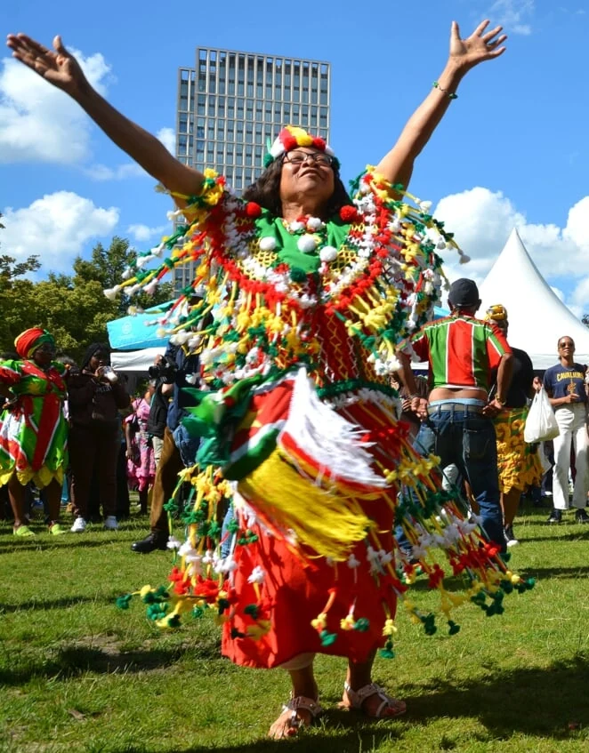 Bezoeker viert Keti Koti met opgeheven armen tijdens het festival in Rotterdam